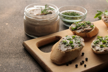 Fresh homemade chicken liver pate with greens on bread on a dark background. A sandwich.