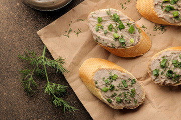 Fresh homemade chicken liver pate with greens on bread on a dark background. view from above