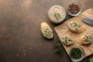 Fresh homemade chicken liver pate with greens on bread on a dark background. view from above