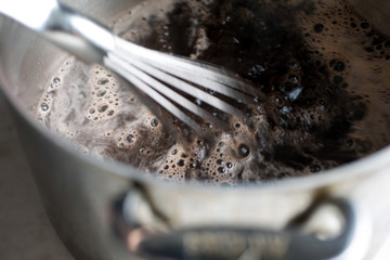 Close up of cocoa solids mixing into simmering water
