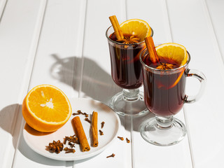 Mulled wine in glass cups and spices in a plate
