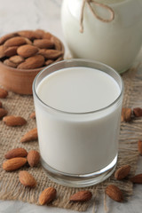 Obraz na płótnie Canvas Fresh almond milk in a glass and almond nuts on a light background