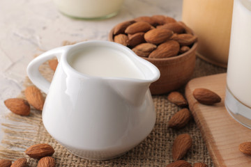 Obraz na płótnie Canvas Fresh almond milk in a milk jug and almond nuts on a light background