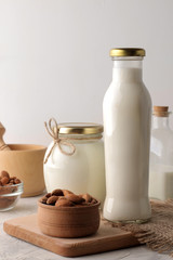 Fresh almond milk in a glass bottle and almond nuts on a light background