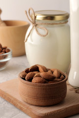 Almond nut in a bowl closeup and almond milk in the background. on a light background