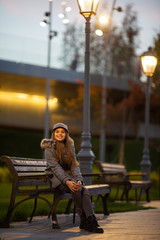 Obraz na płótnie Canvas Photo of girl in gray hat and coat on background of spots, lights, blurred background