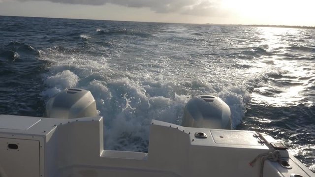 Slow motion view from boat with two outboard motors. Evening cruise with golden sky. Quintana Roo, Mexico.