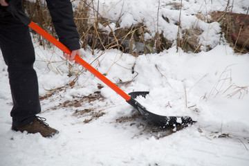 Naklejka premium Clearing snow with a shovel in the winter on the street