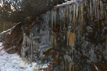 una parete rocciosa avvolta nel ghiaccio invernale con i suoi spuntoni ghiacciati - 233807797