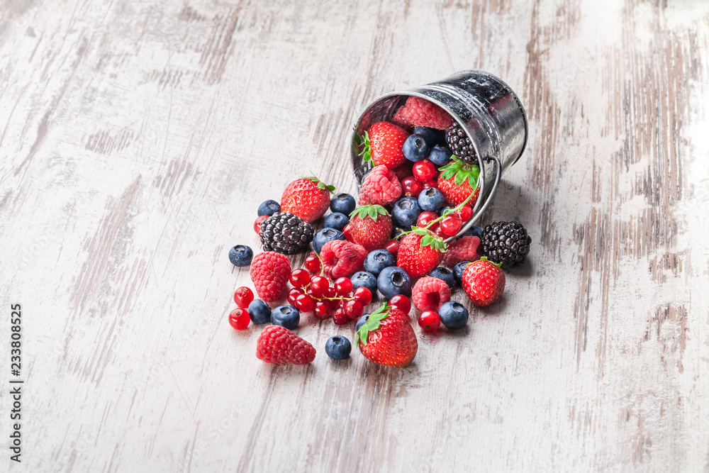 Wall mural Berries arrangement in tin can spilled on white wooden table