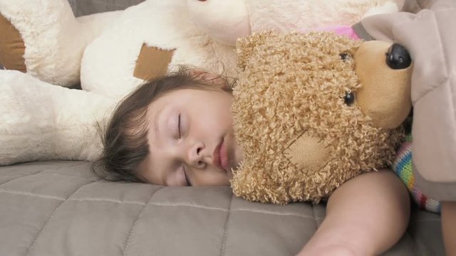 Sleeping cute baby. Beautiful little girl sleeping with toys.
