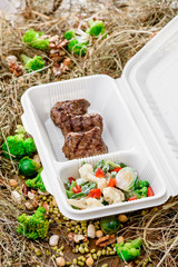 Grilled meat with fresh vegetables. food delivery. Healthy food delivery. Take away for diet. Fitness nutrition, vegetables, meat and fruits in eco boxes. at wood and straw with copy space