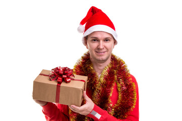 Funny smiling guy with a Santa hat, tinsel around the neck, holding the gift box in the hands