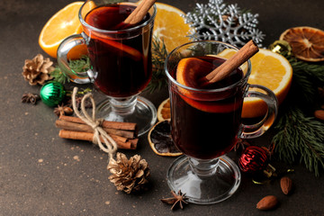 Hot mulled wine with cinnamon and orange in glass cups and Christmas decorations on a dark background. Christmas. new Year.
