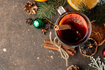 Hot mulled wine with cinnamon and orange in glass cups and Christmas decorations on a dark...