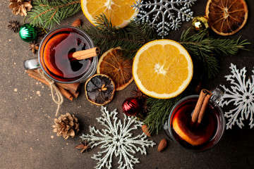 Hot mulled wine with cinnamon and orange in glass cups and Christmas decorations on a dark...