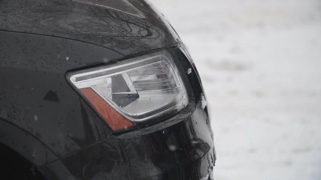 Headlight of black suv vehicle with slow motion snow falling. Winter driving in Canada.