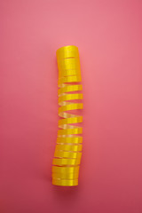 yellow twisted ribbon lies on a pink background.
