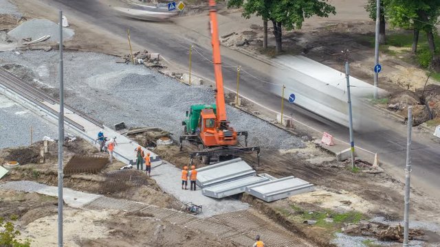 Installing concrete plates by crane at road construction site timelapse.