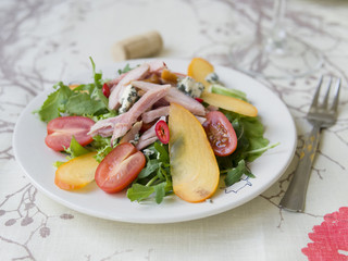 Salad with persimmon, smoked chicken, cherry tomatoes, Camembert cheese and blue cheese sauce. Festive dish . Christmas dinner. Selective focus, closeup, copy space