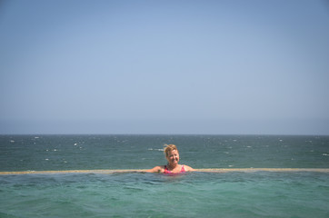 Young Woman in Infinity Pool with Ocean Background