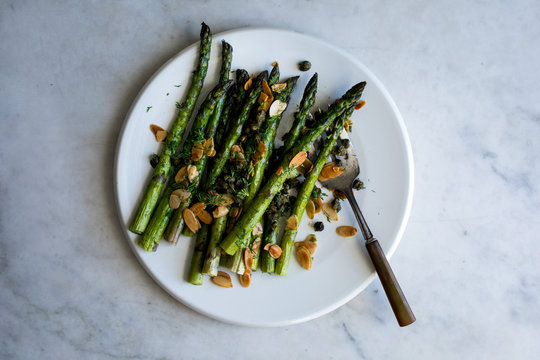 Overhead view of roasted asparagus with almonds, capers and dill