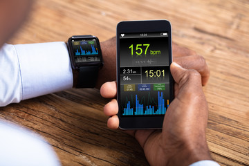 Man With Smartwatch And Cellphone Monitoring Heart Rate