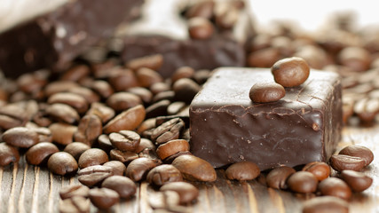 Chocolates and coffee seeds on wooden background