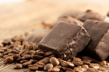 Chocolates and coffee seeds on wooden background