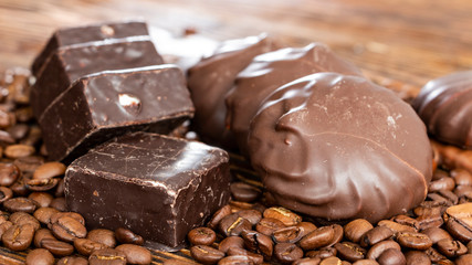 Chocolates and coffee seeds on wooden background