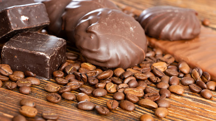 Chocolates and coffee seeds on wooden background