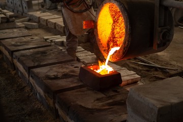 Worker pouring molten metal from flasks into moulds