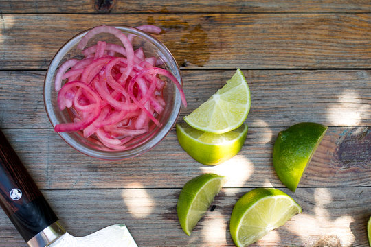 Close up of pickled red onions with lime slices on wooden table