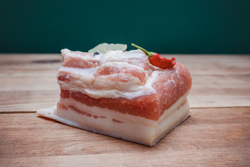 piece of bacon with layers of meat on wooden table.