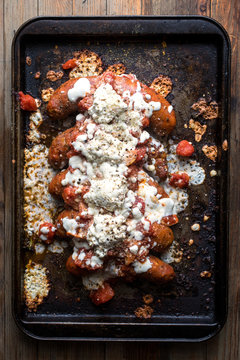 Overhead view of sausage parmesan with garlicky broccoli on baking tray