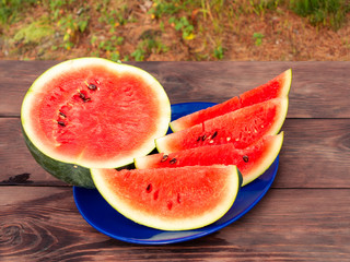 Sliced ripe red watermelon on a blue plate on a wooden table