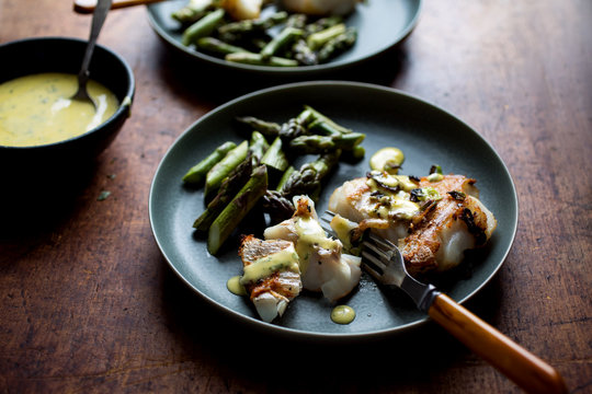 Close up of hake with asparagus and aioli served on plate