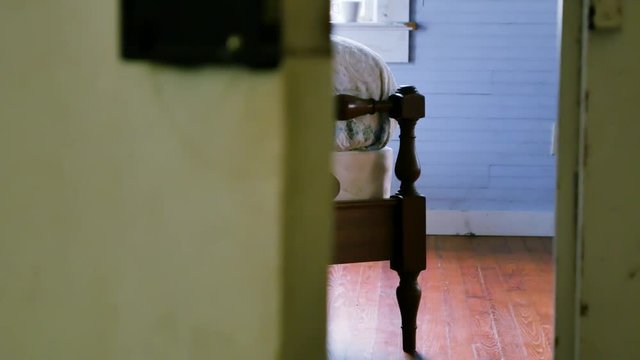 Smooth left to right dolly shot that reveals a vintage wooden bed being bounced and shaking suggestively from activity on the bed.