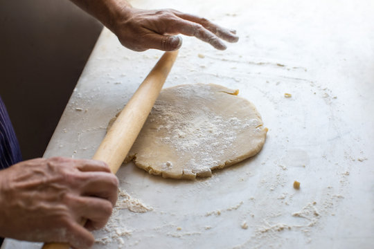 Close Up Of Man's Hand Rolling Dough With Rolling Pin