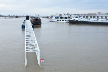 een ondergelopen loopbrug naar een aanlegsteiger door hoogwater in de rivier de Rijn