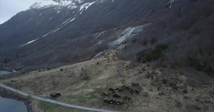 Descending aerial shot of small village in Norwegian wilderness, rooftops covered by moss, Cloudy