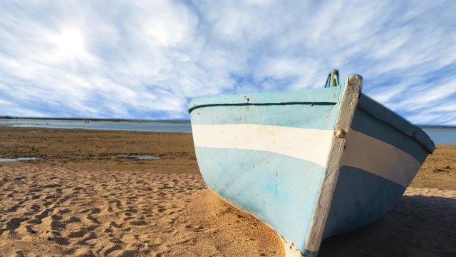 Time lapse of blue fishing boat lie down on a tropical beach with clouds background at beautiful day with calm feeling.