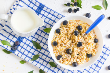 Healthy breakfast. Oatmeal with blueberries, a teaspoon, milk jug with milk, top angle, top view, flatlay