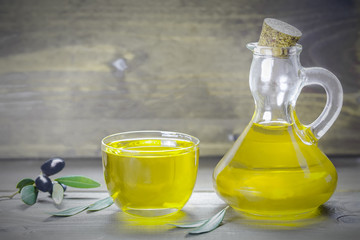 Olive oil and olive branch on the wooden background, apulian olive oil, close up