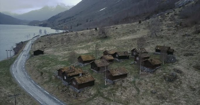 Aerial shot of small fairytale village in Norwegian wilderness, rooftops covered by moss, Cloudy
