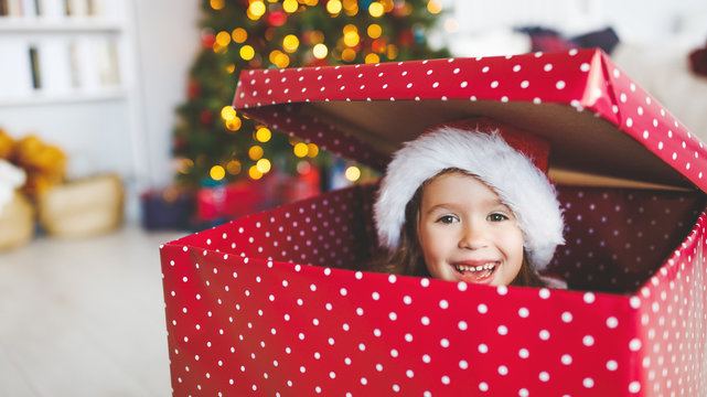 happy funny child girl hiding in big christmas present.