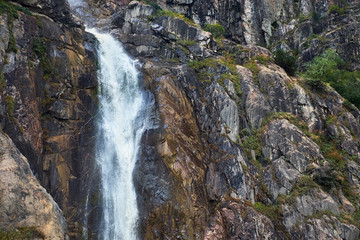 Small glacier icy waterfall in rocky mountains