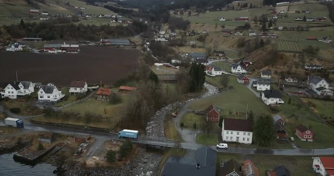 Aerial shot of Cars passing small bridge over stream in Utvik village, Norway
