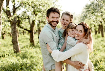 Fototapeta premium Portrait of a happy family with male and female children in the apple orchard