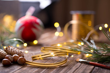 Fototapeta na wymiar Christmas card. gift preparation, with nice light background, decorated golden strap, brush and huzelnuts.